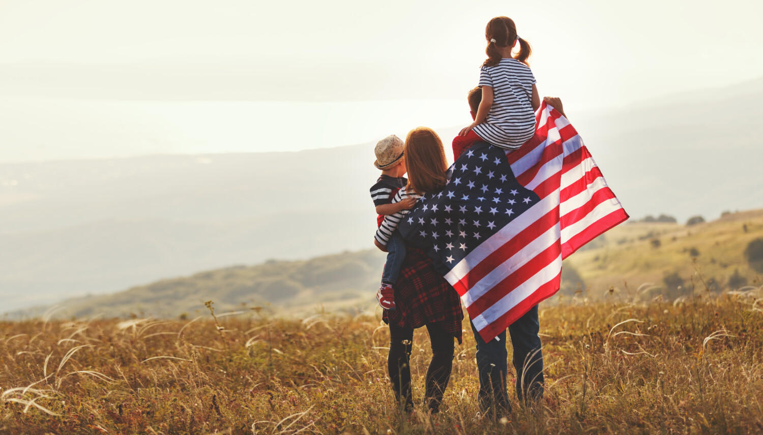 stock-photo-happy-family-with-the-flag-of-america-usa-at-sunset-outdoors-1117095815